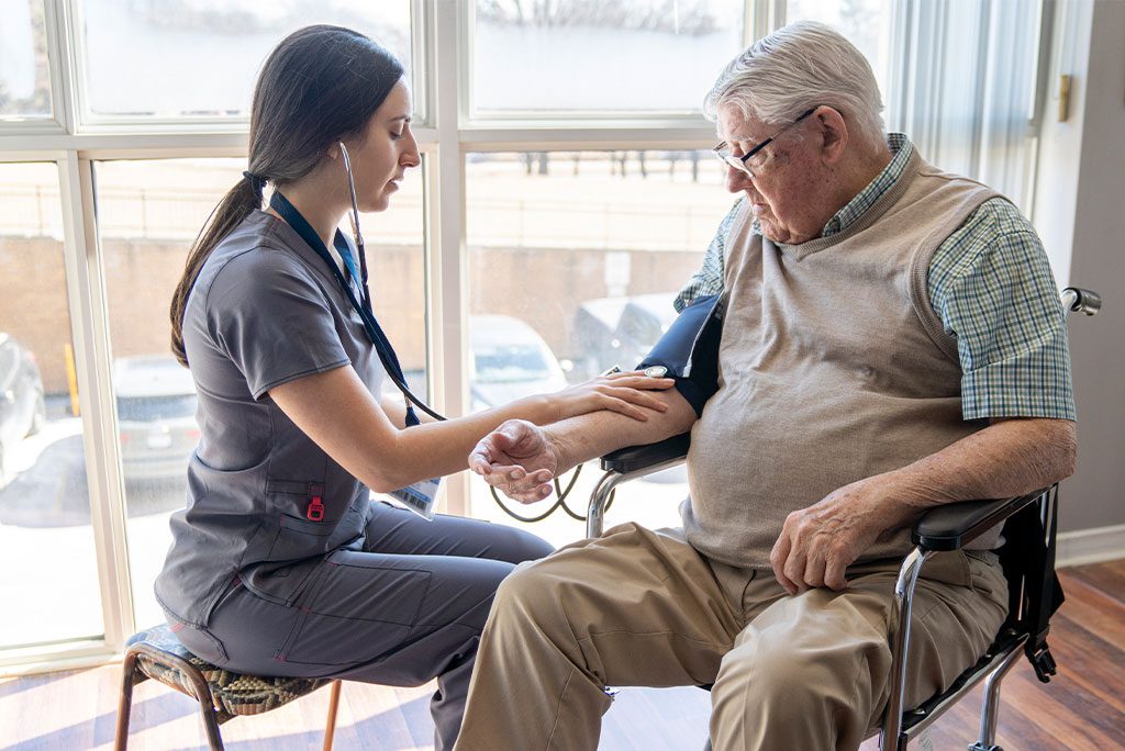 A female nurse checks a senior man's blood pressure.