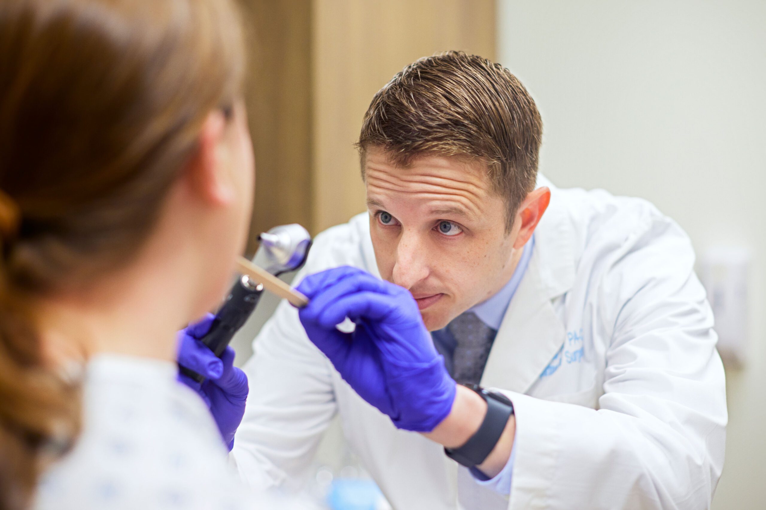 A medical professional uses a tongue depressor to look at a patient's throat.